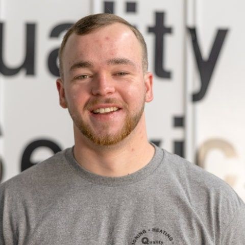 Smiling person in a gray shirt with text in the background.