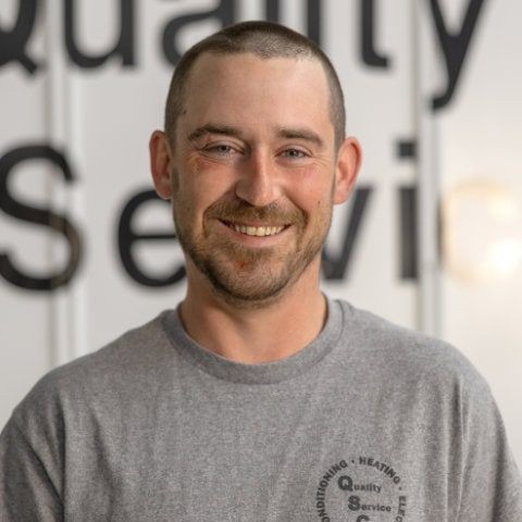 Smiling person wearing a gray shirt with 'Quality Service' text in the background.