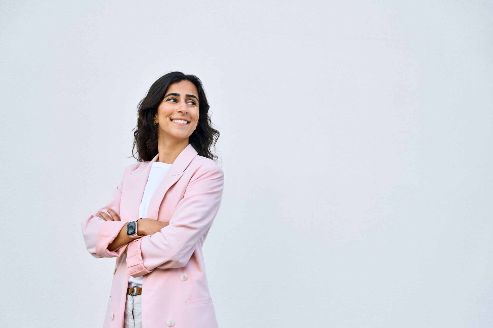 Portrait of middle eastern Israel businesswoman, business lady standing with crossed arms isolated on white background. Smiling 30s young Arabian or Indian woman in suit, looking aside at copy space