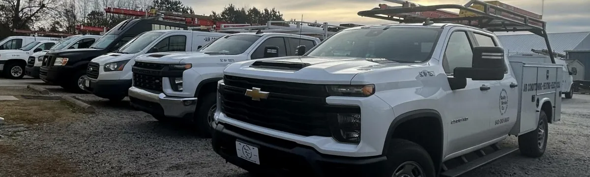 QSC service trucks are parked in a row with ladders on their racks.