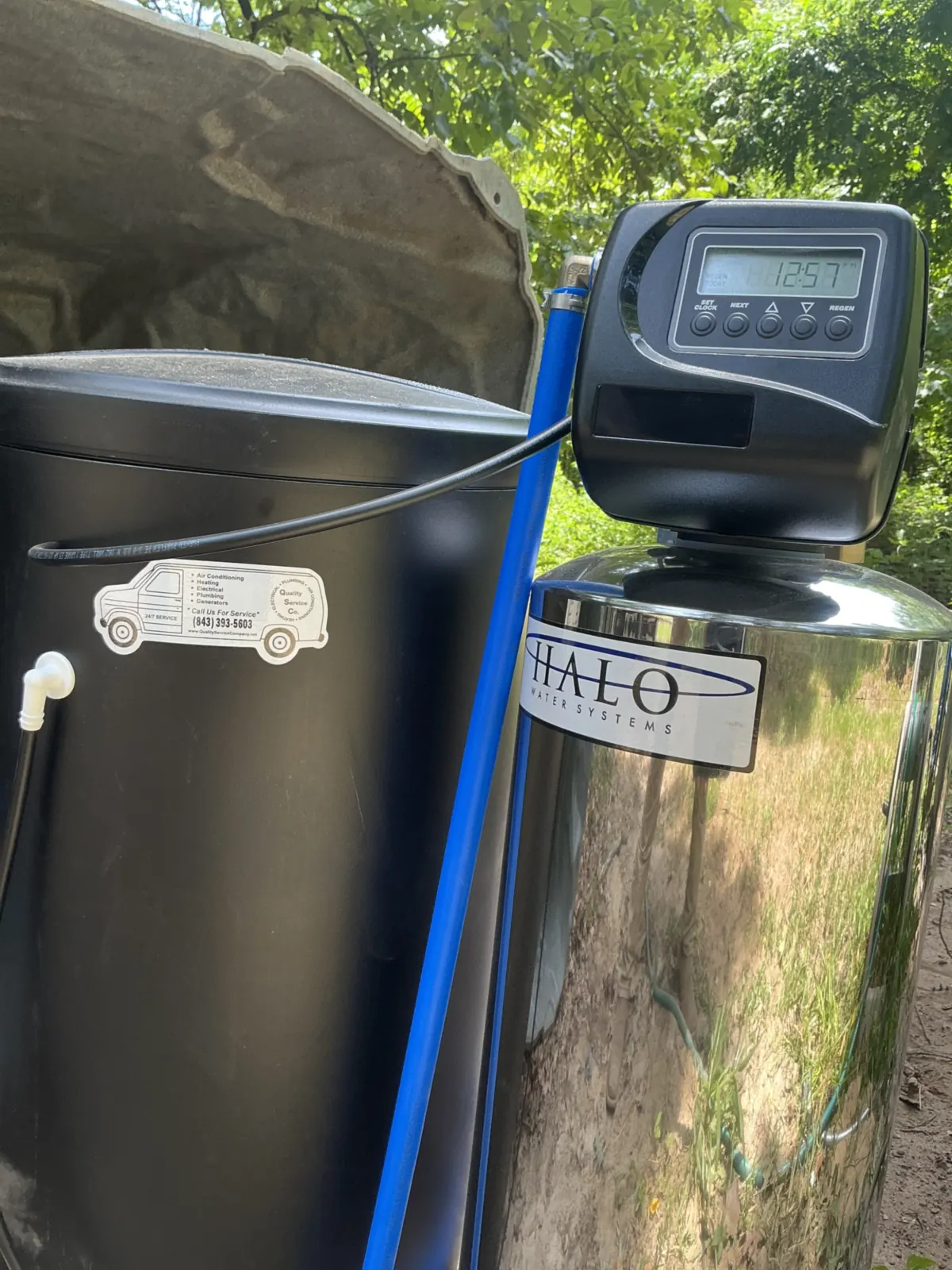 A Halo controller and treatment tank stand beside a Quality Service Company service sticker.