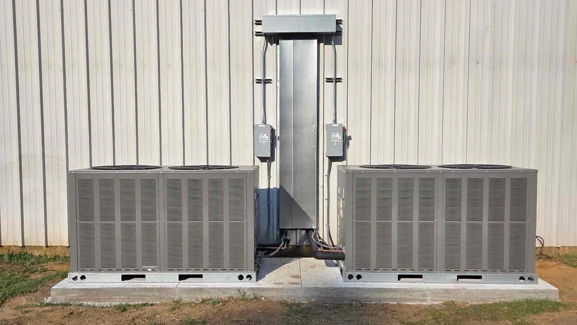 Two outdoor condensers sit beside a light corrugated wall.