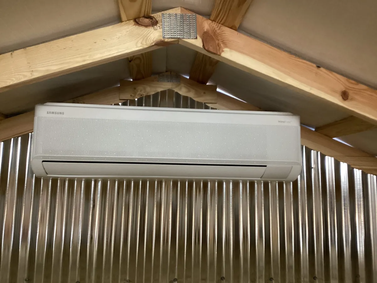 A wall-mounted mini-split sits beneath timber rafters.