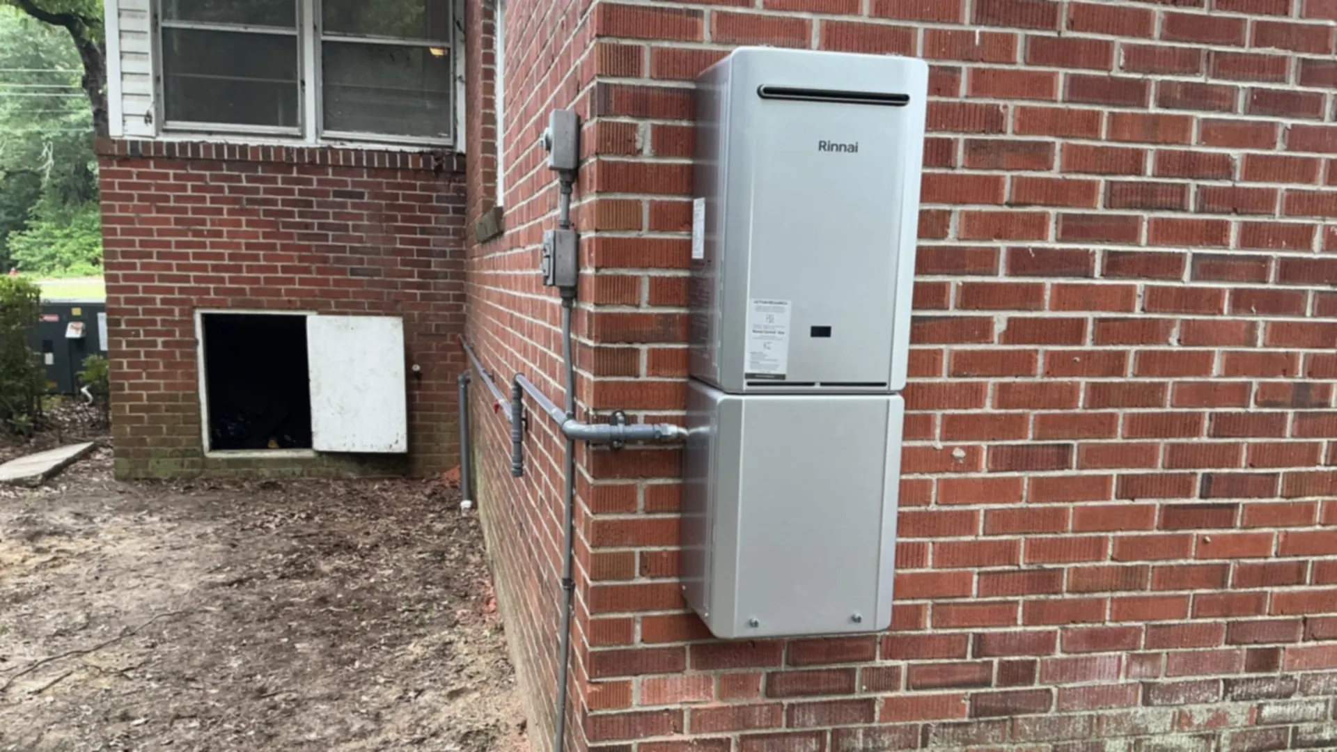 A Rinnai tankless water heater is mounted on a red-brick wall.