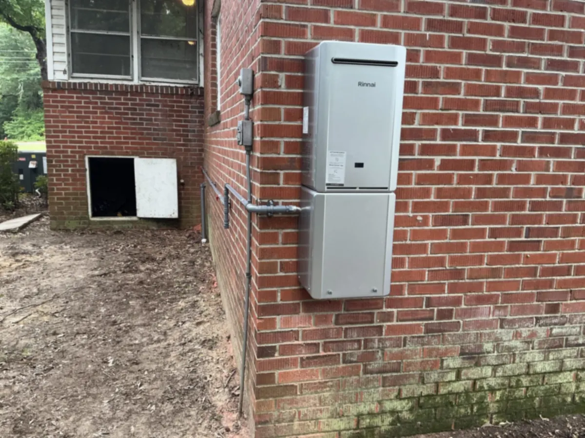 A Rinnai tankless water heater is mounted on a red-brick wall.